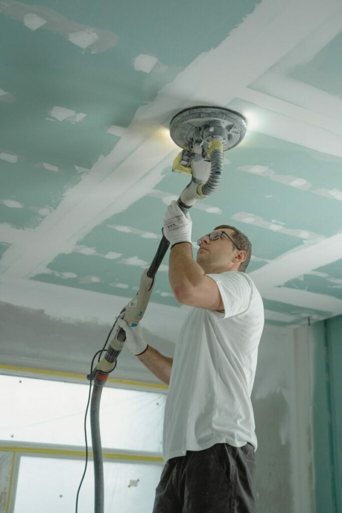 travaux de rénovation d'un plafond avec une ponceuse